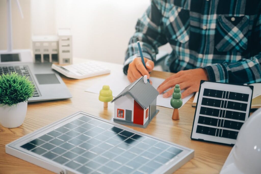 Solar energy professional planning a residential solar panel system with a model home and panel samples.